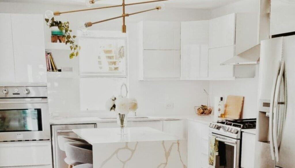 A bright, modern kitchen featuring white cabinetry, stainless steel appliances, and minimalist decor.