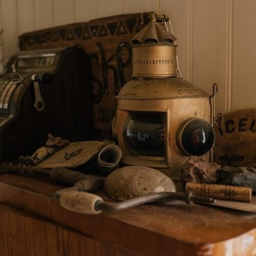 A collection of vintage items including a cash register and a lantern on a wooden cabinet.