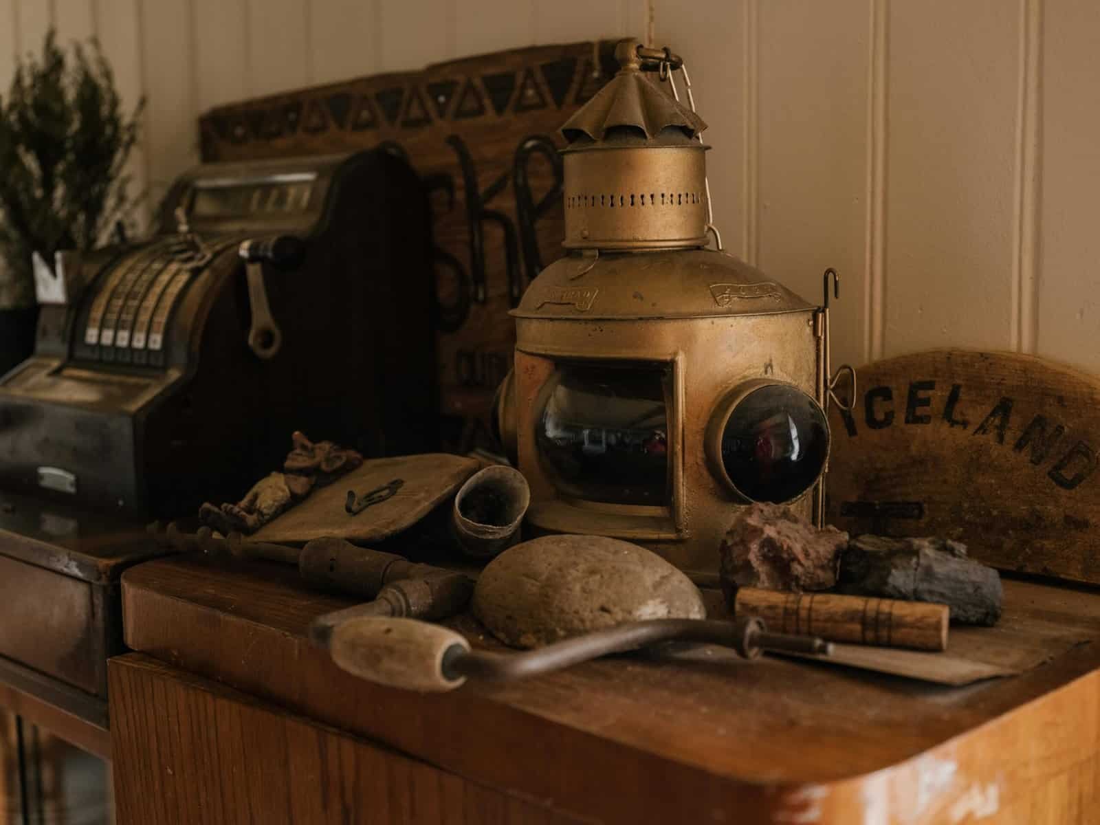 A collection of vintage items including a cash register and a lantern on a wooden cabinet.